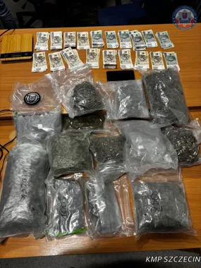 Zabezpieczone przez szczecińską policję worki z suszem roślinnym, gotówka i waga leżą na stole w pomieszczeniu służbowym.